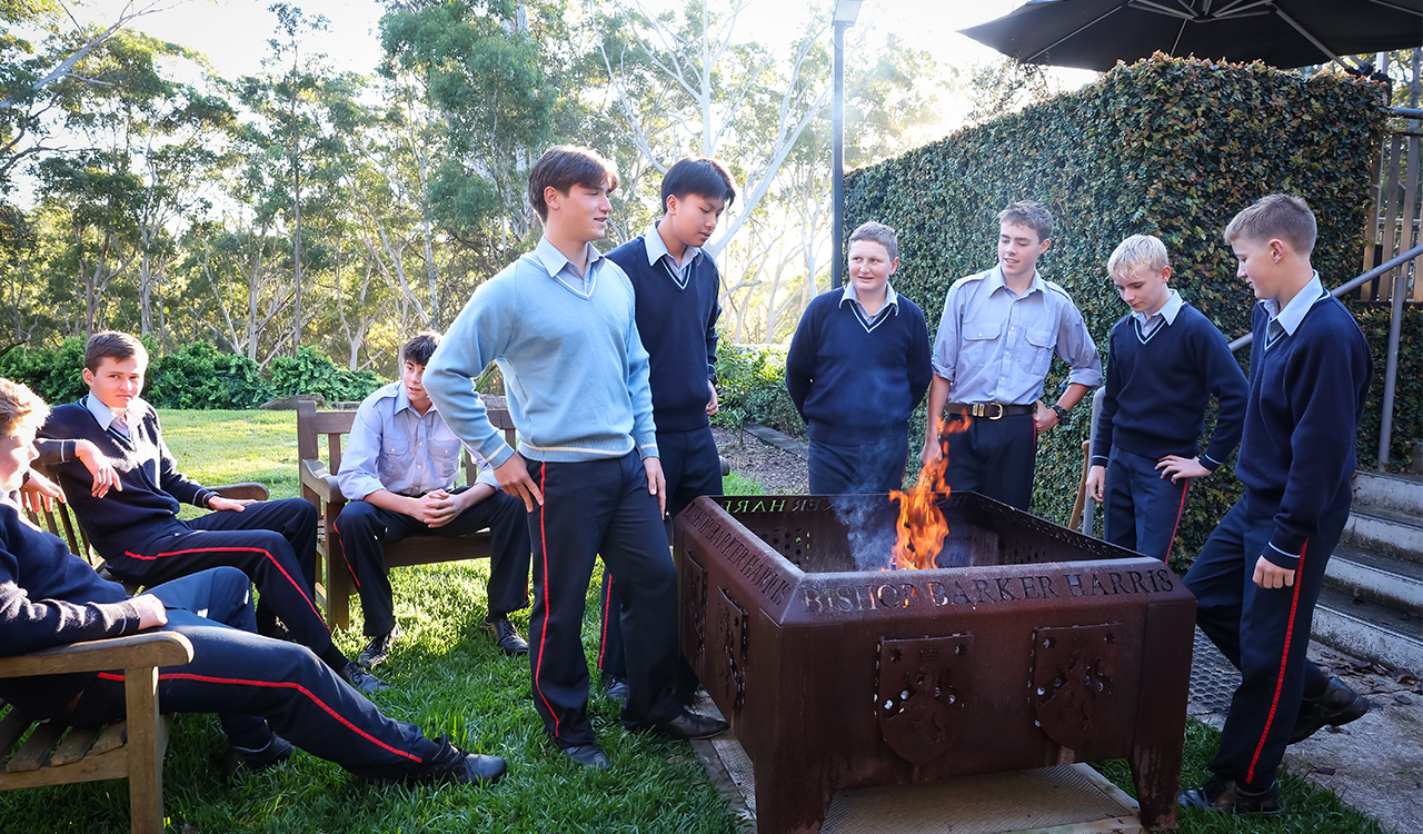 Boarders in uniform standing outside around a fire pit