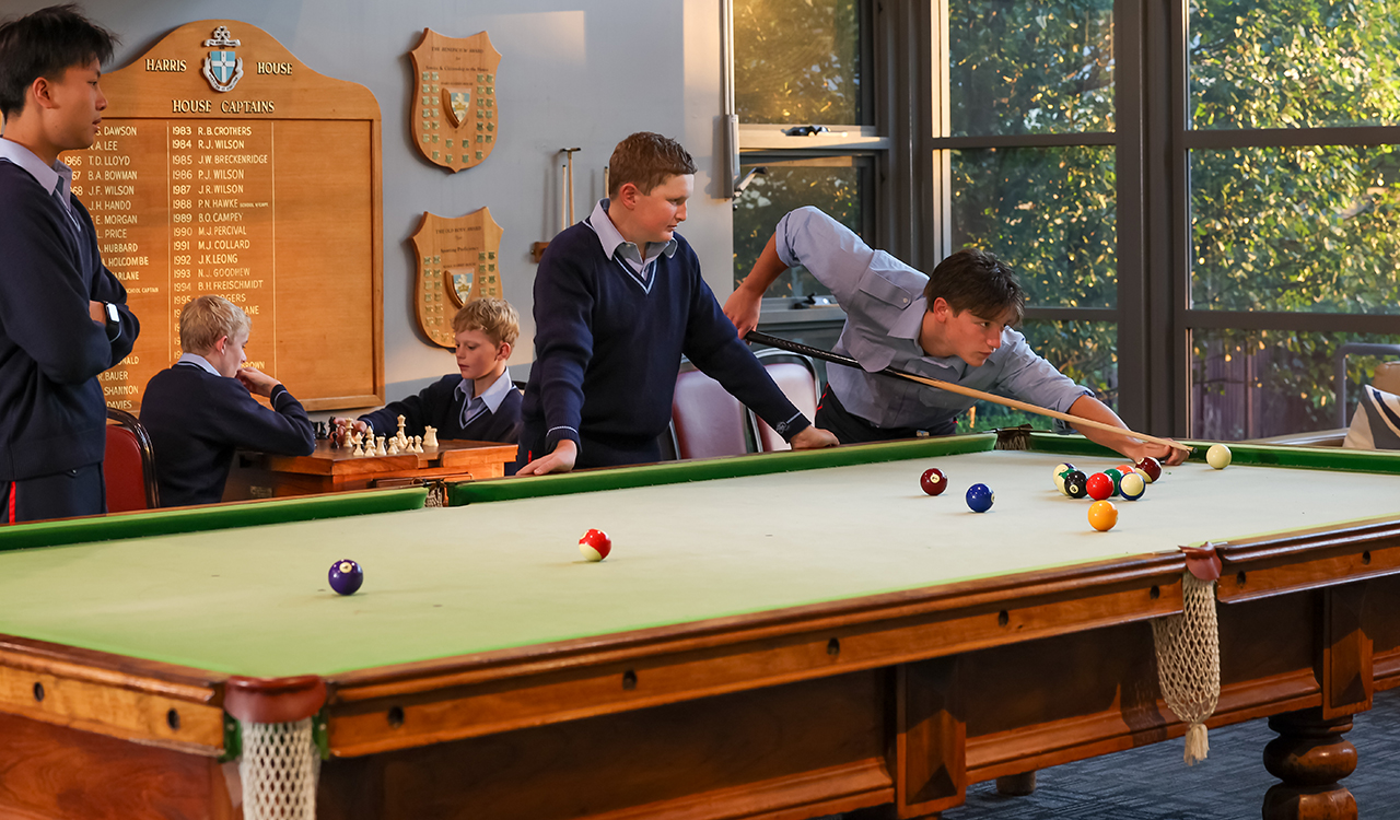 Young men in uniform playing pool and chess in the background