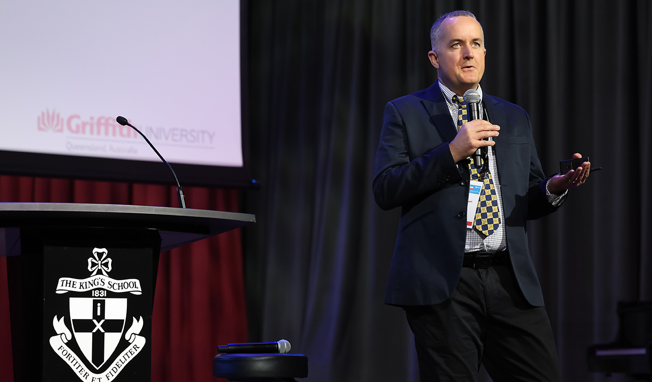 Man speaking with microphone addressing a hall of teachers