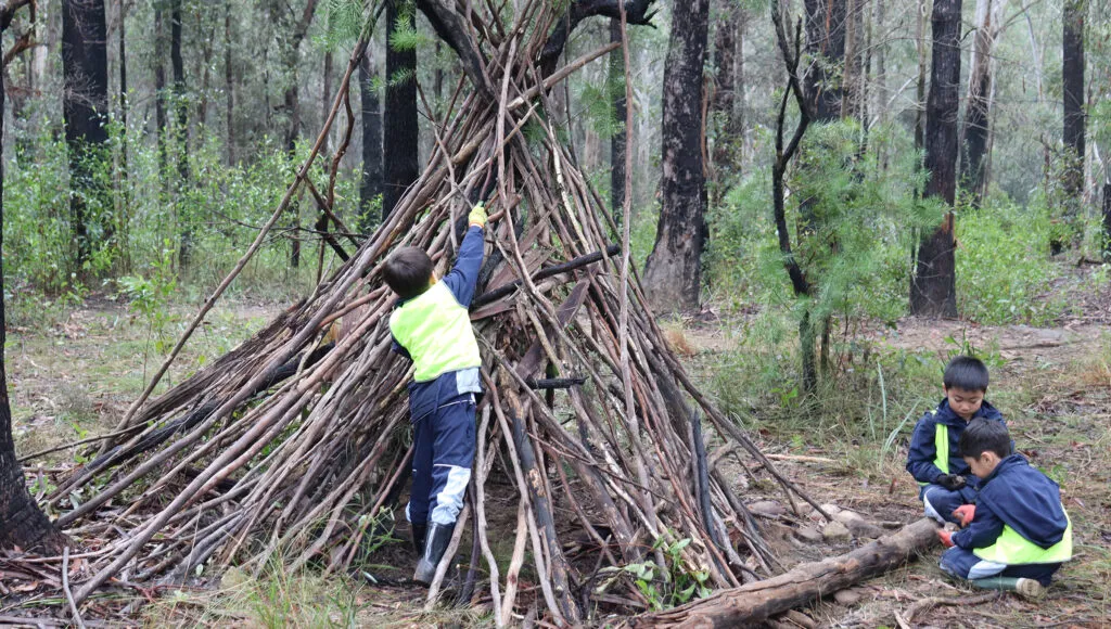 Young children putting sticks together in bush